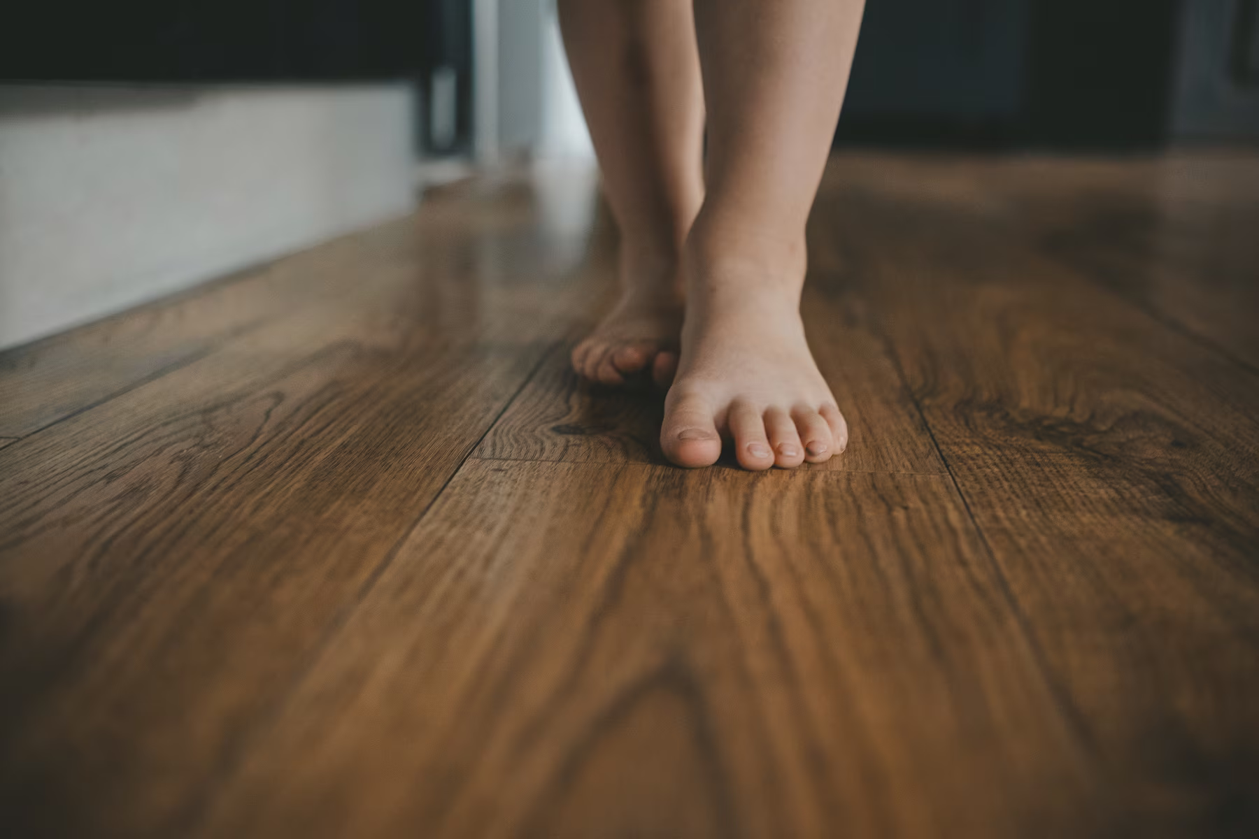 Bare feet walking across a freshly cleaned wood floor.